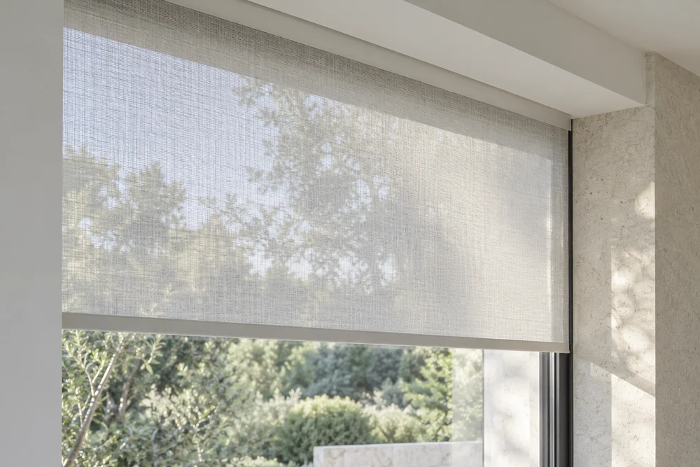 Daylight filters through a woven sheer roller shade concealed within a clean window recess.